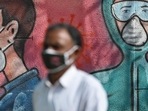A pedestrian wearing a face mask walks past a wall mural depicting frontline Covid-19 coronavirus warriors. A pedestrian wearing a face mask walks past a wall mural depicting frontline Covid-19 coronavirus warriors.