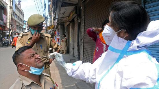 A healthcare worker takes a swab sample of a police personnel amid rising Covid cases at Bharat Mata Chowk in Jammu on Thursday. (ANI) A healthcare worker takes a swab sample of a police personnel amid rising Covid cases at Bharat Mata Chowk in Jammu on Thursday. (ANI)