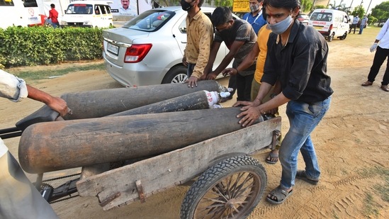 Workers unload oxygen cylinders at the Commonwealth Games (CWG) Village Covid-19 Care Centre, in New Delhi, on April 21. The daily case trajectory has now grown 62% in the last week, HT reported.(Raj K Raj / HT Photo)