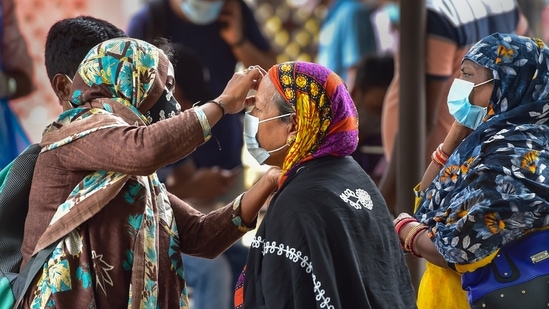 A woman helps an old lady to wear face mask at Bengaluru City Railway Station amid surge in coronavirus cases, in Bengaluru. (PTI)