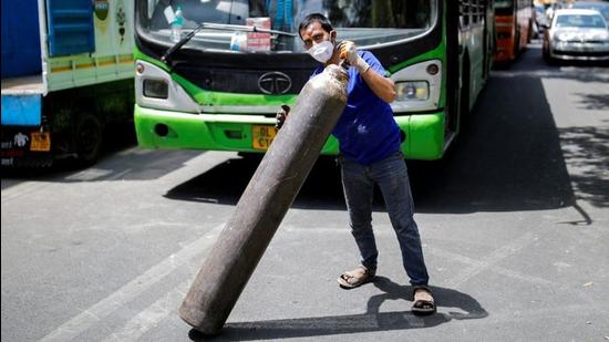 A man carries a filled oxygen cylinder to load into a truck for a hospital outside a private refilling station. (REUTERS)