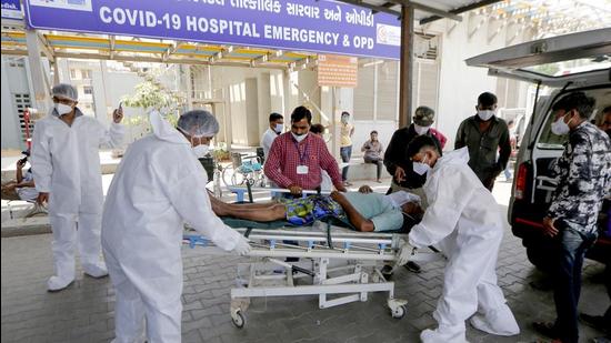 Health workers carry a Covid-19 patient to the OPD ward of a hospital, as cases surge in record numbers across the country, in Ahmedabad. (PTI) Health workers carry a Covid-19 patient to the OPD ward of a hospital, as cases surge in record numbers across the country, in Ahmedabad. (PTI)