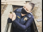 The image shows the officer rescuing a duckling.