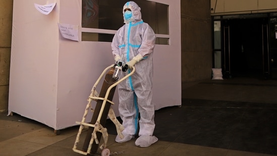 A healthcare worker pushes a trolley holding an oxygen tank at a temporary hospital for Covid-19 patients at a stadium in New Delhi, (Bloomberg) A healthcare worker pushes a trolley holding an oxygen tank at a temporary hospital for Covid-19 patients at a stadium in New Delhi, (Bloomberg)