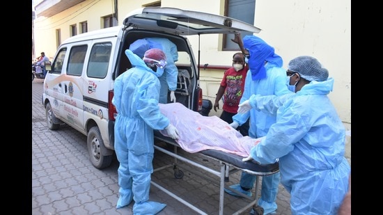 Health workers putting a body into a vehicle after six Covid patients died at Neelkanth Hospital in Amritsar, on Saturday. (Sameer Sehgal /Hindustan Times)