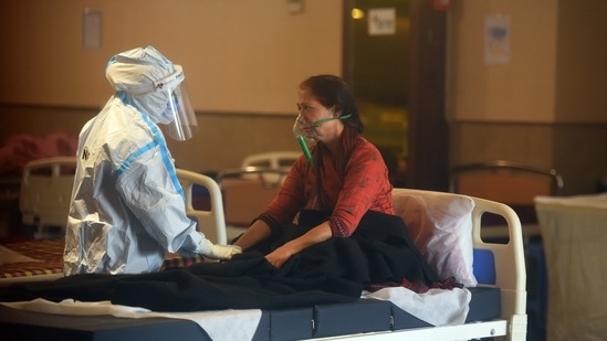 Medical staff in PPE attending to a person in the temporary Covid-19 care centre attached to LNJP Hospital in New Delhi on April 23. At the national level, the average positivity rate has gone from 4.2% a month ago to 18.4% in the week ending April 22 – a rise of 14.2 percentage points. A rising positivity rate as tests increase is the worst possible scenario from an epidemiological perspective.(Raj K Raj / HT Photo)