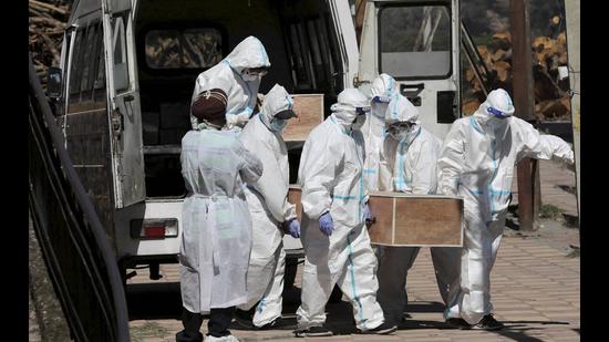 Health workers and family members in protective suits carrying bodies of Covid-19 victims for cremation in Jammu on Saturday. (PTI) Health workers and family members in protective suits carrying bodies of Covid-19 victims for cremation in Jammu on Saturday. (PTI)