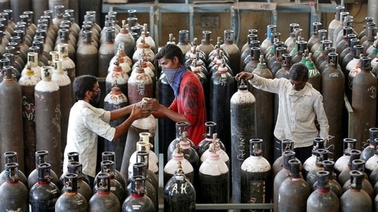 People carry oxygen cylinders after refilling them in a factory, amidst the spread of the coronavirus disease in Gujarat's Ahmedabad. (Reuters Photo)