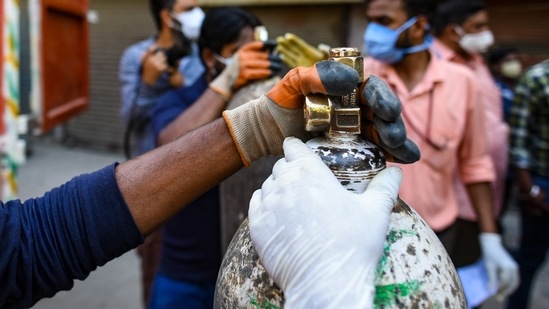People hold onto a medical oxygen cylinder near GTB Hospital, in New Delhi, on April 24. The authorities scrambled to get oxygen tanks to hospitals where Covid-19 patients were gasping amid the world’s worst Covid-19 surge, as many criticised alleged government negligence over the public health crisis spiralling out of control.(Amal KS / HT Photo)