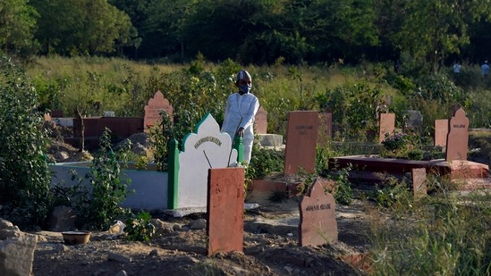 A child stands by the graves of loved ones who died due to Covid-19, at Jadid Qabristan Ahle Islam, in New Delhi, on April 24. The death toll in the national capital mounted to 13,898. The case fatality rate was at 1.38%, HT reported.(Sanjeev Verma / HT Photo)