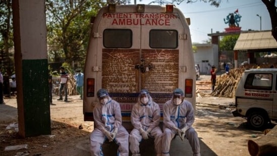 Exhausted workers, who bring dead bodies for cremation, sit on the rear step of an ambulance inside a crematorium, in New Delhi, India, Saturday, April 24, 2021. (AP)