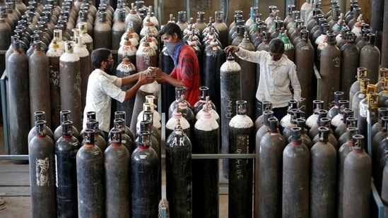 People carry oxygen cylinders after refilling them in a factory, amidst the spread of the coronavirus disease (COVID-19) in Ahmedabad. (Reuters)