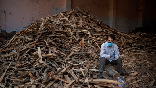 A man sits on a log while waiting for the funeral of his relative who died of Covid-19, at a ground that has been converted into a crematorium for mass cremation of Covid-19 victims in New Delhi on April 24. The toll, which is India’s highest in a single day period, makes it yet another day when more than 2000 people lost their lives.(Altaf Qadri / AP)