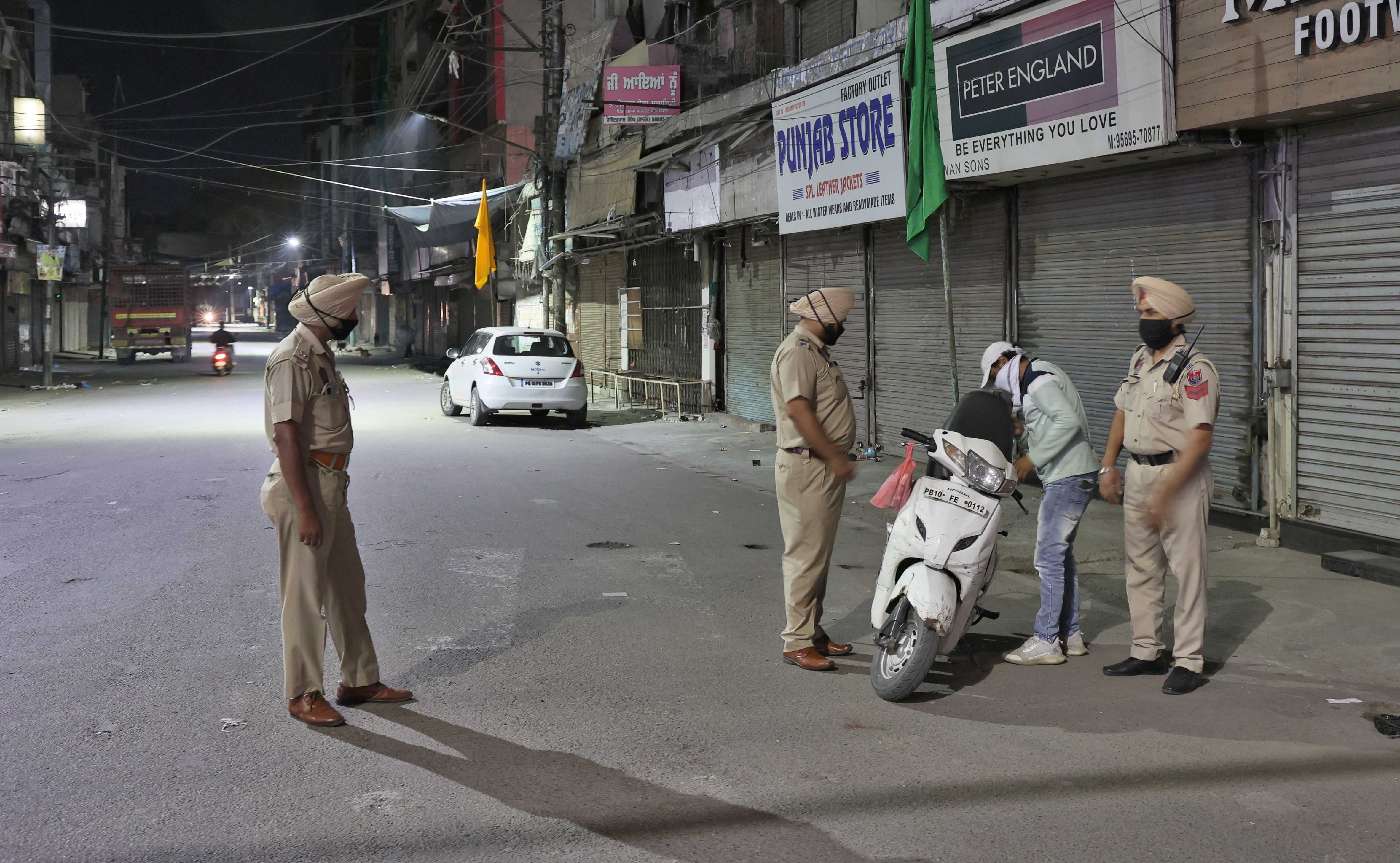 Punjab Police personnel checking the documents of a scooter rider during the night curfew in Ludhiana. (Gurpreet Singh/HT file photo)