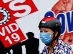 A woman wearing a protective mask drives past a banner promoting prevention against Covid-19 in Hanoi, Vietnam.(Reuters)