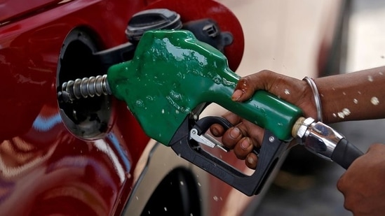 A worker holds a nozzle to pump petrol into a vehicle at a fuel station in Mumbai, India.(Reuters)