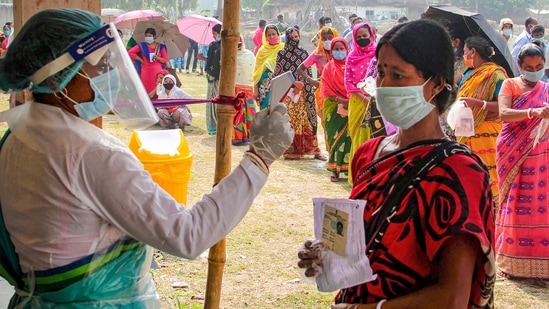 A health worker sanitises voters as they wait in queues to cast votes at a polling station during the 7th phase of West Bengal Assembly elections at a village near Balurghat in South Dinajpur district, Monday, April 26, 2021. (PTI)