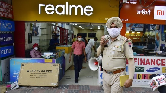 A cop making an announcement regarding the 5pm deadline for closure of shops at Hall Bazar in Amritsar on Tuesday. (Sameer Sehgal /HT) A cop making an announcement regarding the 5pm deadline for closure of shops at Hall Bazar in Amritsar on Tuesday. (Sameer Sehgal /HT)