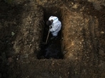 A man in a protective suit digs earth to bury the body of a person who died of Covid-19 in Guwahati on April 25. India's toll from the coronavirus surged past 200,000 on April 28, after what were the country's deadliest 24-hours in terms of deaths from the disease yet.(Anupam Nath / AP)