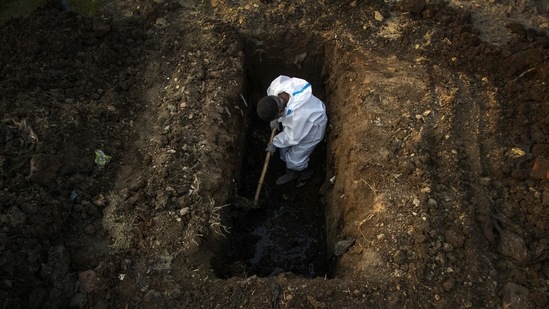 A man in a protective suit digs earth to bury the body of a person who died of Covid-19 in Guwahati on April 25. India's toll from the coronavirus surged past 200,000 on April 28, after what were the country's deadliest 24-hours in terms of deaths from the disease yet.(Anupam Nath / AP)