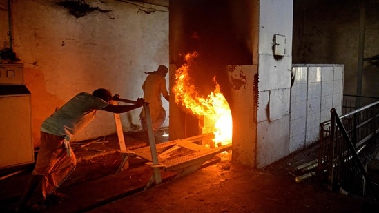 A worker pushes a trolley that carried the body of patient who died of the Covid-19 coronavirus into a furnace during the cremation at an electric crematorium in Allahabad on April 27. Makeshift crematorium facilities in parks and parking lots have had to be made in several places to accommodate the dead where bodies burn on rows of funeral pyres.(Sanjay Kanojia / AFP)