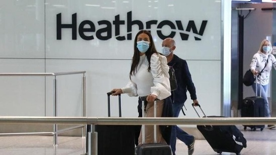 Passengers, wearing protective face masks, walk through the international arrivals hall after arriving at Terminal 2 at London Heathrow Airport in London, UK. Passengers, wearing protective face masks, walk through the international arrivals hall after arriving at Terminal 2 at London Heathrow Airport in London, UK.