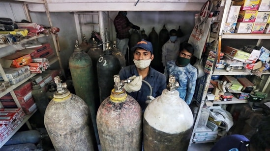 Workers filling oxygen cylinders at an oxygen agency in New Delhi on April 25. Officials and Delhi Police personnel have meanwhile also launched crackdowns after receiving reports of black marketing and pilfering of oxygen supplies.(ANI)