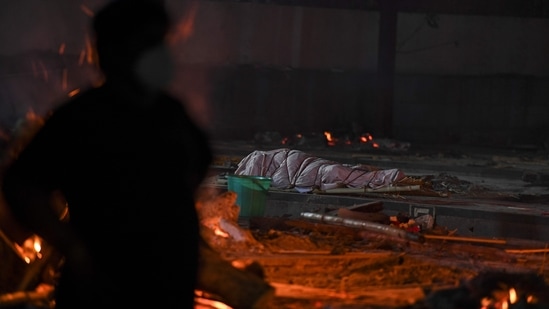 The dead body of a Covid-19 coronavirus victim lays before cremation next to pyres of other victims at Nigambodh Ghat Crematorium in New Delhi on April 28, 2021. (AFP)