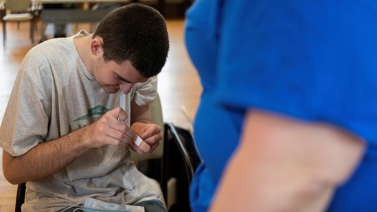 Michael Farris, 21, who is on the autism spectrum, prepares a band-aid after receiving a coronavirus disease (COVID-19) vaccine at Variety - the Children?s Charity of the Delaware Valley during a vaccine clinic on their campus in conjunction with Skippack Pharmacy in Worcester, Pennsylvania, U.S., April 29, 2021.(REUTERS)