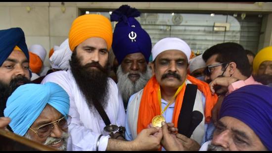 Sikh preacher and Haryana Sikh Gurdwara Parbandhak Committee (HSGPC) president Baljit Singh Daduwal felicitating former Punjab Police inspector general Kunwar Vijay Pratap Singh with a gold medal outside Golden Temple in Amritsar on Friday. (Sameer Sehgal/HT)