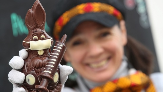 Belgian artisan chocolate maker Genevieve Trepant shows a chocolate bunny wearing a protective mask and holding a vaccine syringe called "L'Atch'a Azteka" at her workshop Cocoatree.(REUTERS)