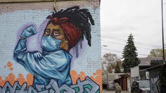 A person walking a dog passes a mural dedicated to healthcare workers in Toronto, Ontario, Canada. (Bloomberg)