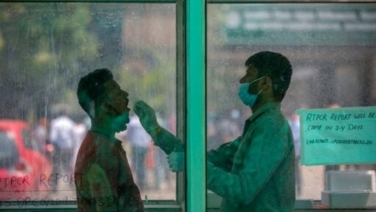 A health worker takes a swab sample to test for Covid-19 at a government hospital in Noida. (AP Photo) A health worker takes a swab sample to test for Covid-19 at a government hospital in Noida. (AP Photo)