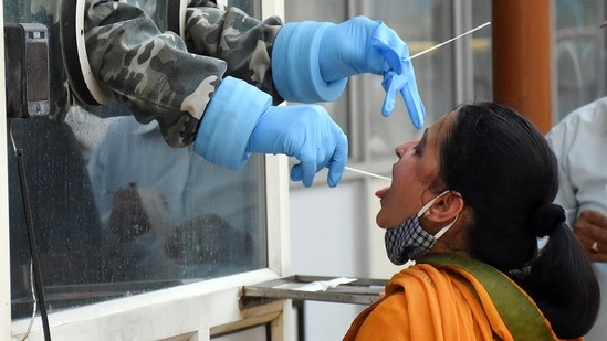 A health worker collects a swab sample from a woman at Ram Manohar Lohiya Hospital in Lucknow. (ANI Photo)