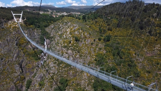 People walk across a narrow footbridge suspended across a river canyon, which claims to be the world's longest pedestrian bridge, in Arouca, northern Portugal, Sunday, May 2, 2021. The Arouca Bridge inaugurated Sunday, offers a half-kilometer (almost 1,700-foot) walk across its span, some 175 meters (574 feet) above the River Paiva. (AP) People walk across a narrow footbridge suspended across a river canyon, which claims to be the world's longest pedestrian bridge, in Arouca, northern Portugal, Sunday, May 2, 2021. The Arouca Bridge inaugurated Sunday, offers a half-kilometer (almost 1,700-foot) walk across its span, some 175 meters (574 feet) above the River Paiva. (AP)