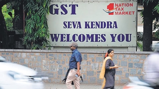 Pedestrians walk in front of a board advertising Goods and Service Tax (GST) in front of the Central Goods and Service Tax office in Bangalore.(AFP/For Representative Purposes Only)