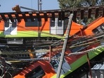 Workers move a train car from a site where an overpass for a metro partially collapsed with train cars on it at Olivos station in Mexico City on May 4, 2021. 