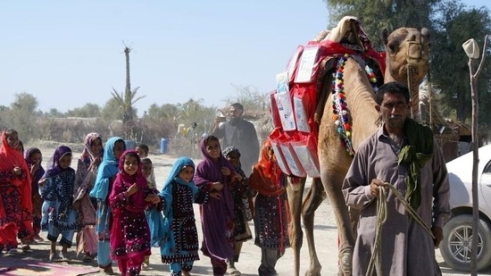 Children react as Roshan the camel carries books in Mand, Pakistan.(via REUTERS)