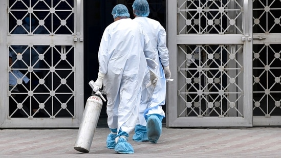 A health worker in PPE carrying an a oxygen cylinder at Lok Nayak Jai Prakash (LNJP) Hospital, in New Delhi, India. (Sanjeev Verma/HT Photo)