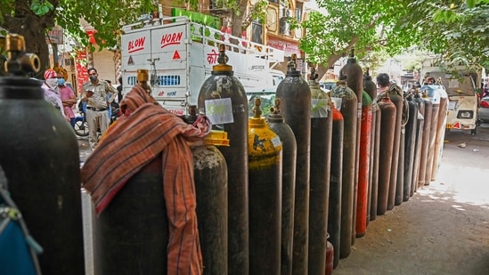 People wait to refill their medical oxygen cylinders for the Covid-19 coronavirus patients under home quarantine at a private refill center in New Delhi on May 4, 2021, as India's total Covid caseload soared past 20 million. (Photo by Prakash SINGH / AFP)