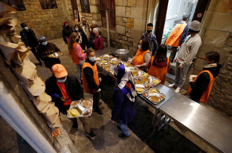 People carry food trays during a charity Ramadan dinner in the cloister at Santa Anna church during the coronavirus disease (COVID-19) outbreak, in Barcelona, Spain