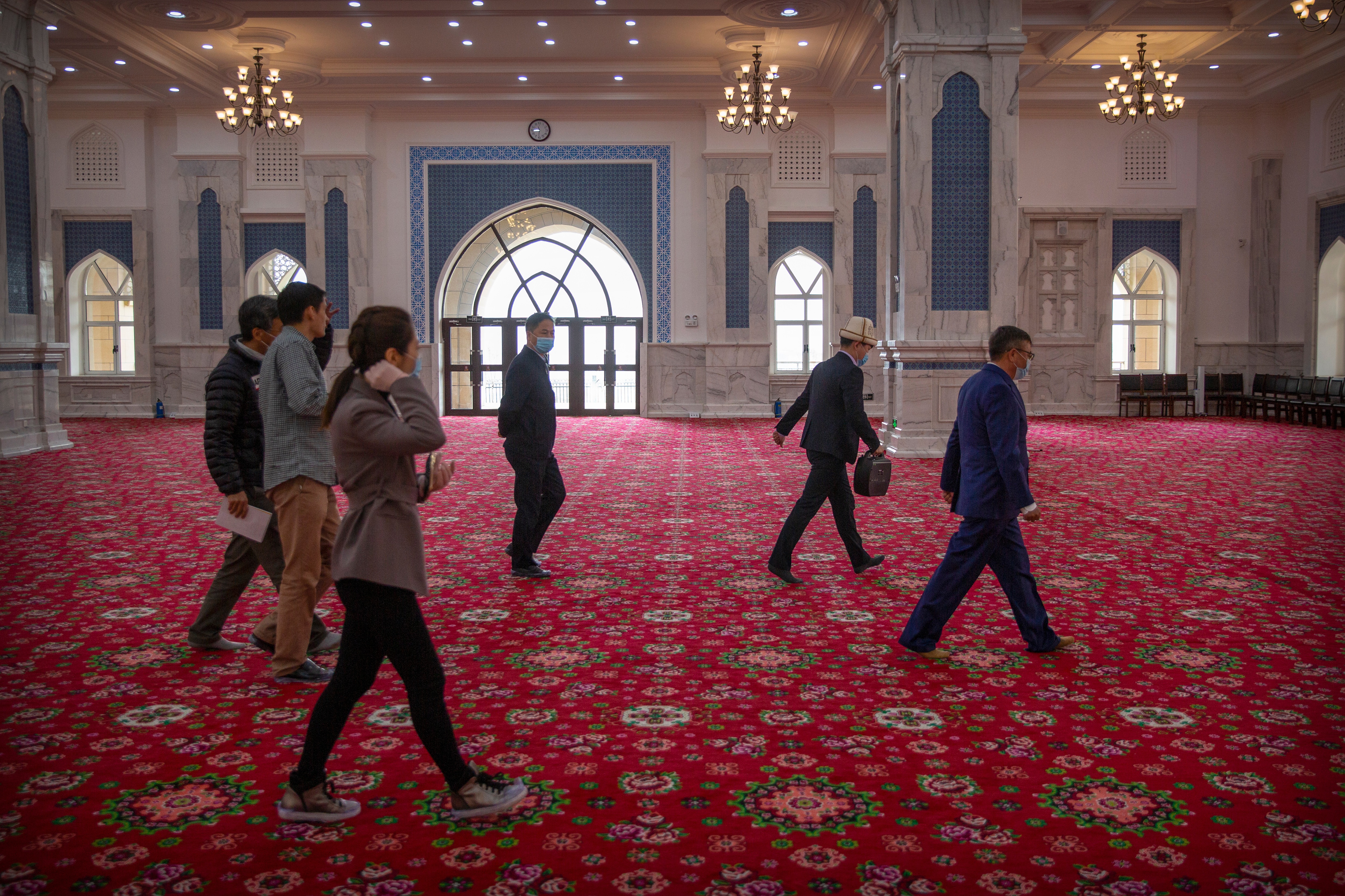 Abit Qazbay, right, an instructor at the Xinjiang Islamic Institute, and government officials walk through the prayer hall during a government organized visit for foreign journalists at the institute's campus in Urumqi in western China's Xinjiang Uyghur Autonomous Region, on April 22, 2021. (AP) Abit Qazbay, right, an instructor at the Xinjiang Islamic Institute, and government officials walk through the prayer hall during a government organized visit for foreign journalists at the institute's campus in Urumqi in western China's Xinjiang Uyghur Autonomous Region, on April 22, 2021. (AP)