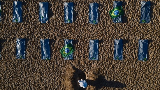 An activist from the NGO "Rio de Paz" digs a mock grave in the sand by symbolic body bags on Copacabana beach to protest the government's handling of the Covid-19 pandemic, in Rio de Janeiro, Brazil on April 30. Deaths go unreported as most countries only record those that occur in hospitals or of patients with confirmed infection, Reuters reported citing IHME analysis.(Lucas Dumphreys / AP)