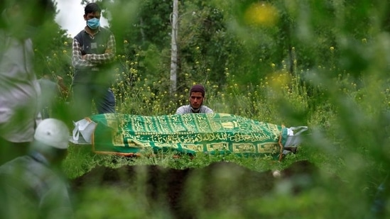 Relatives seen next to the body of a Covid-19 victim during a burial on the outskirts of Srinagar on May 4. The reported Covid-19 mortality is strongly related to the levels of testing in a country, the IHME said.(Danish Ismail / REUTERS)