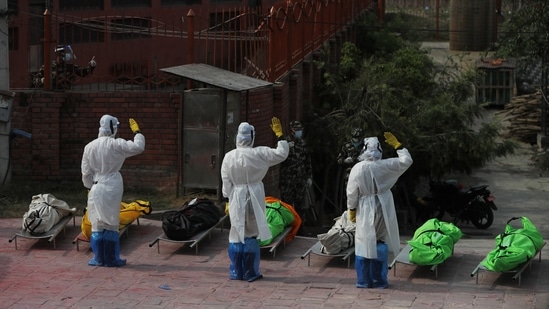 Nepalese army personnel in PPE pay tribute to Covid-19 victims before cremating their bodies near Pashupatinath temple in Kathmandu, Nepal on May 7. IHME estimated total COVID-19 deaths by comparing anticipated deaths from all causes based on pre-pandemic trends with the actual number of all deaths caused during the pandemic.(Niranjan Shrestha / AP)