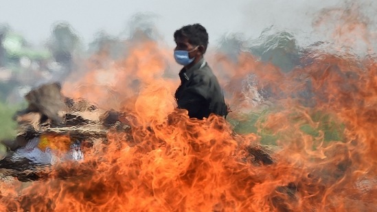 A worker walks past a burning funeral pyre of a person who died due to the Covid-19 coronavirus at a cremation ground in Allahabad on May 8, 2021, as India recorded more than 4,000 coronavirus deaths in a day for the first time. (AFP) A worker walks past a burning funeral pyre of a person who died due to the Covid-19 coronavirus at a cremation ground in Allahabad on May 8, 2021, as India recorded more than 4,000 coronavirus deaths in a day for the first time. (AFP)