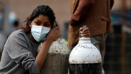 A woman holds on to the oxygen cylinders for a patient after refiling them at a factory, amidst the spread of coronavirus disease (Covid-19) in Kathmandu, Nepal. (REUTERS)