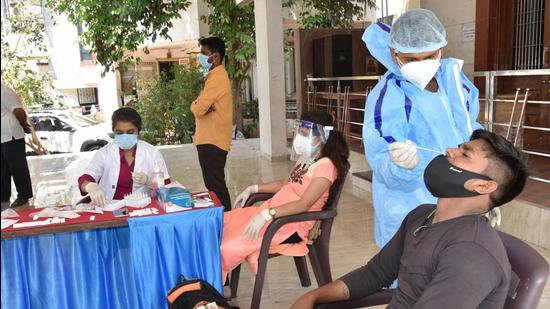 A medic collects a swab sample for RT-PCR test. Readers state that authorities should arrange more testing centres. (HT PHOTO)