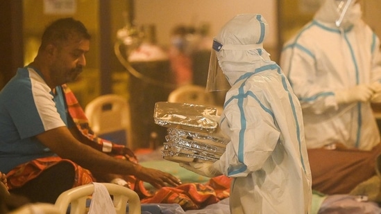 Health workers wearing personal protective equipment (PPE kit) attends to Covid-19 coronavirus positive patients inside a banquet hall temporarily converted into a covid care centre in New Delhi.(AFP)