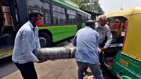 Men loading oxygen cylinders into an autorickshaw at Sarojini Nagar Bus Depot in New Delhi on May 9. Delhi had logged 11,491 fresh cases of the infection on April 12, and recorded a test positivity rate of 19.69% on April 16.(Sanjeev Verma / HT Photo)